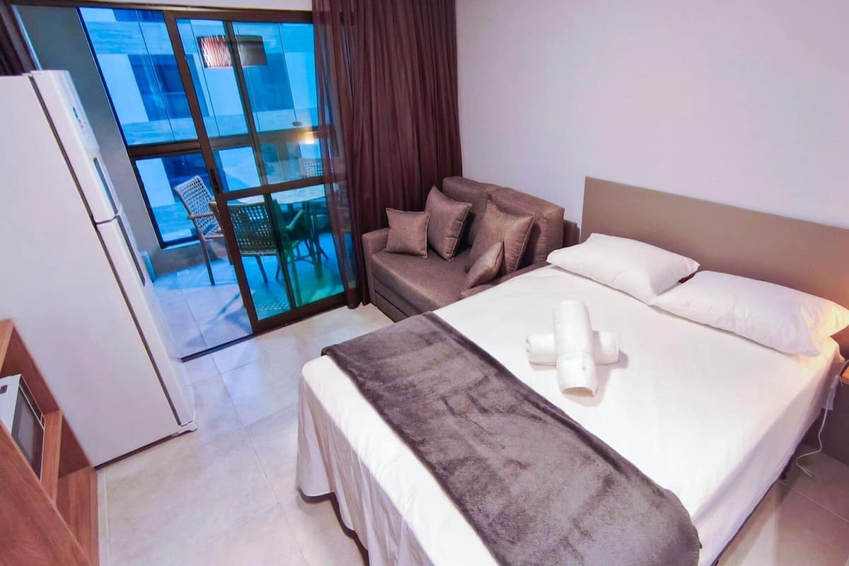 Ein Hotelzimmer mit Bett, Sofa, Schreibtisch und Blick ins Freie.