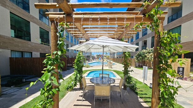 An outdoor seating area with a pool, surrounded by wooden pergolas and greenery.