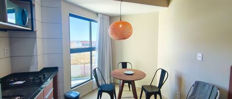 A modern kitchen with a microwave, stove, and dining area with chairs and a table.