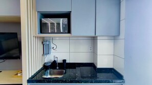 Eine kleine Küche mit Mikrowelle, Spüle und Arbeitsplatte.