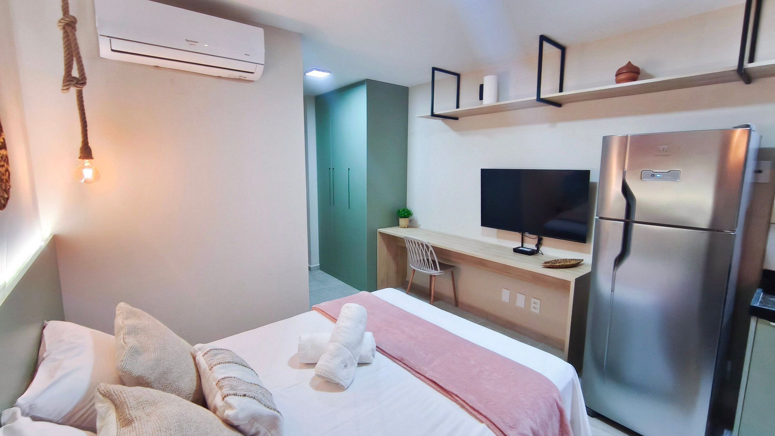 A hotel room with a bed, a desk, a television, and a refrigerator.