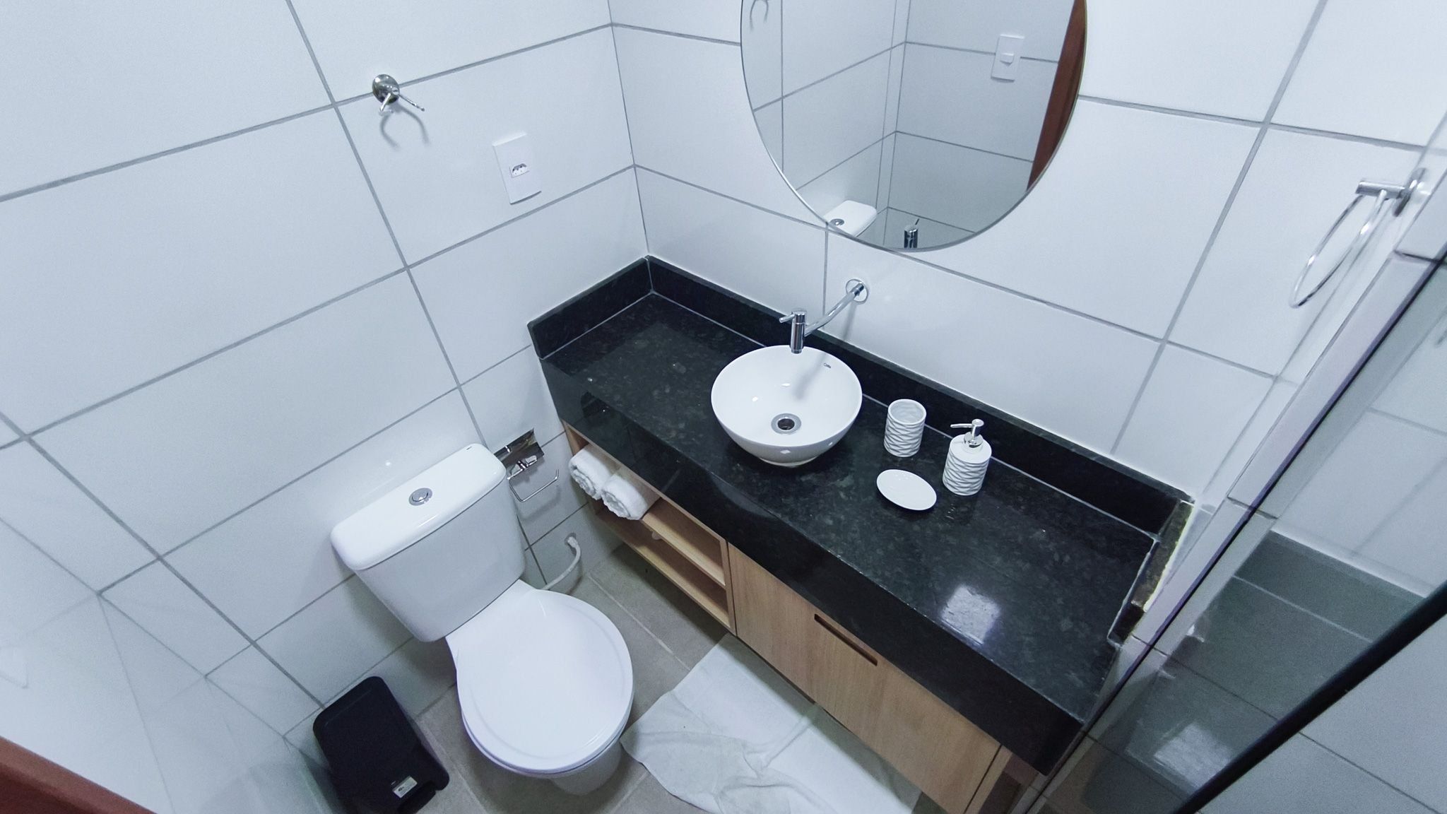 Et badeværelse med toilet, vask, spejl og bordplade i sort.