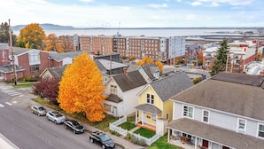A residential area with houses, a street, and a view of the water and mountains in the distance.