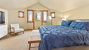 A bedroom with a large bed, a chair, a desk, and a TV.