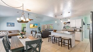 A spacious living area with a dining table and chairs, a kitchen with a central island, and a seating area with a sofa and chairs. - Fantastic 3-bedroom house with private heated pool (Nokomis)