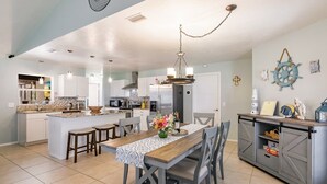 A spacious kitchen with a central island, a dining area with a wooden table, and a grey cabinet with shelves. - Fantastic 3-bedroom house with private heated pool (Nokomis)