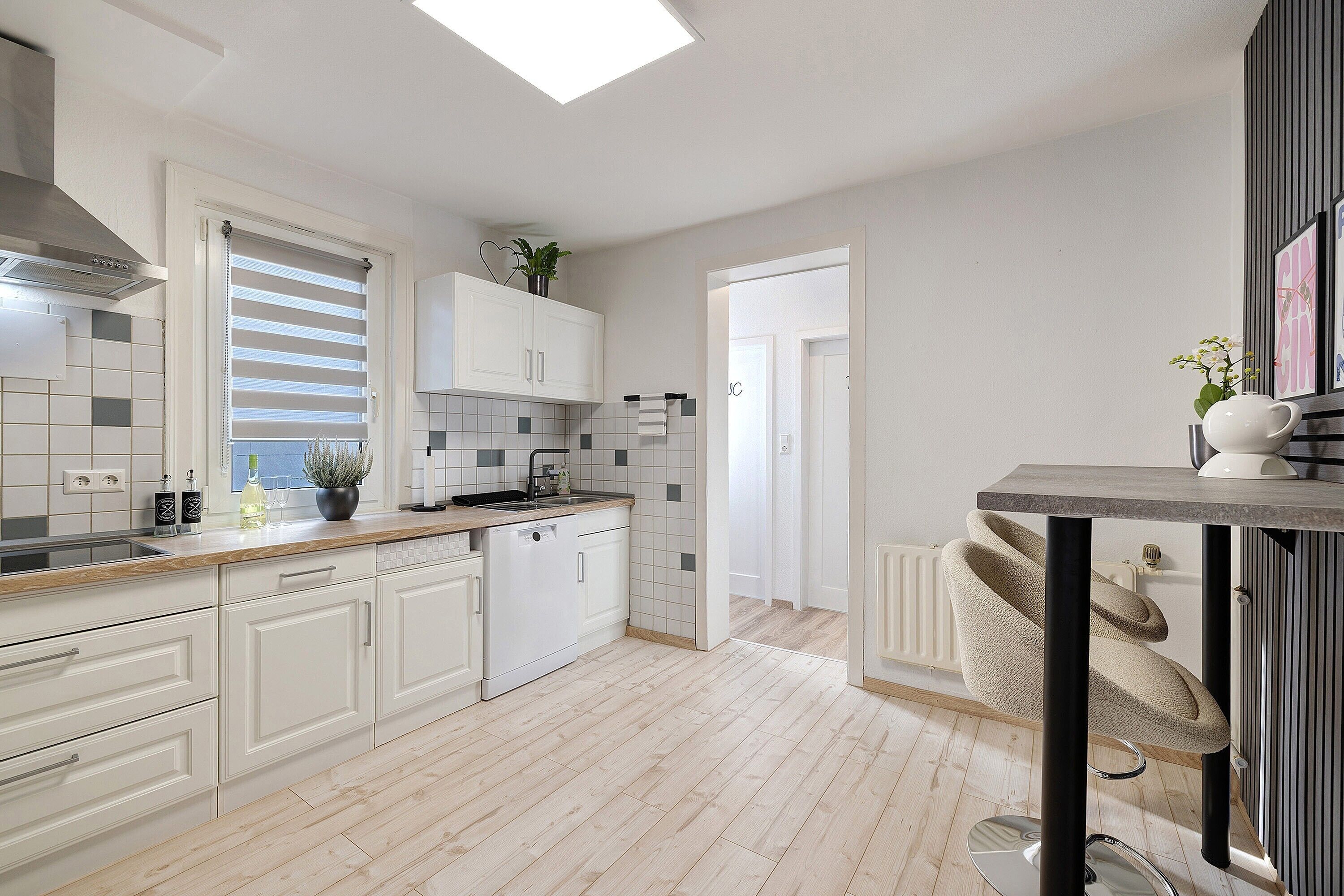 Een moderne keuken met witte kasten, een dakraam en uitzicht op de aangrenzende kamer.