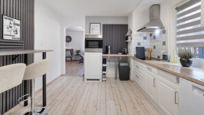 Una cocina moderna con una isla central, armarios blancos y un comedor con taburetes de bar.