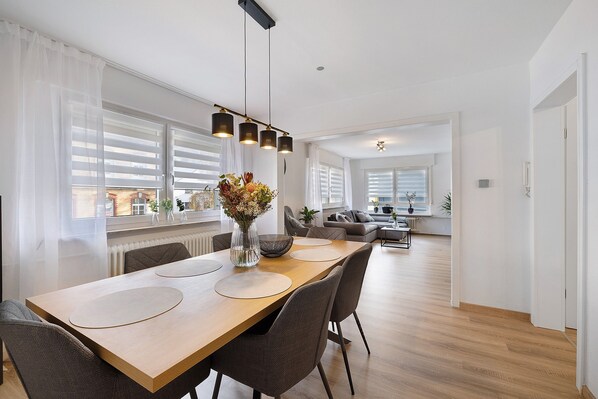 Un espace repas moderne avec une table en bois, des chaises et un vase de fleurs.