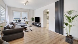 Una sala de estar moderna con un sofá, televisor y plantas en macetas.