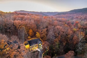 A large, dark-colored house surrounded by a forest with autumn foliage. - Skylark Luxe|9BR,7 Suites,Speakeasy,Sauna,Sleeps22 (McGaheysville)