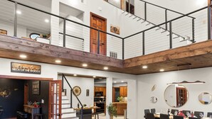 A multi-level interior with a dining area, kitchen, and a staircase leading to a loft. - Skylark Pines-Luxury 8BR/5.5BA Massanutten Retreat (McGaheysville)