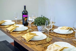 A dining table set with white plates, gold napkins, and wine glasses, with a bottle of wine and a small plant on the table. - Skylark Luxe|9BR,7 Suites,Speakeasy,Sauna,Sleeps22 (McGaheysville)