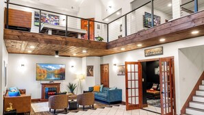 A spacious, multi-level living area with a wooden ceiling, a large chandelier, and a fireplace. - Skylark Pines-Luxury 8BR/5.5BA Massanutten Retreat (McGaheysville)