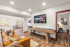 A modern living room with a wooden coffee table, a brown leather sofa, and a large flat-screen TV mounted on the wall. - Skylark Luxe|9BR,7 Suites,Speakeasy,Sauna,Sleeps22 (McGaheysville)