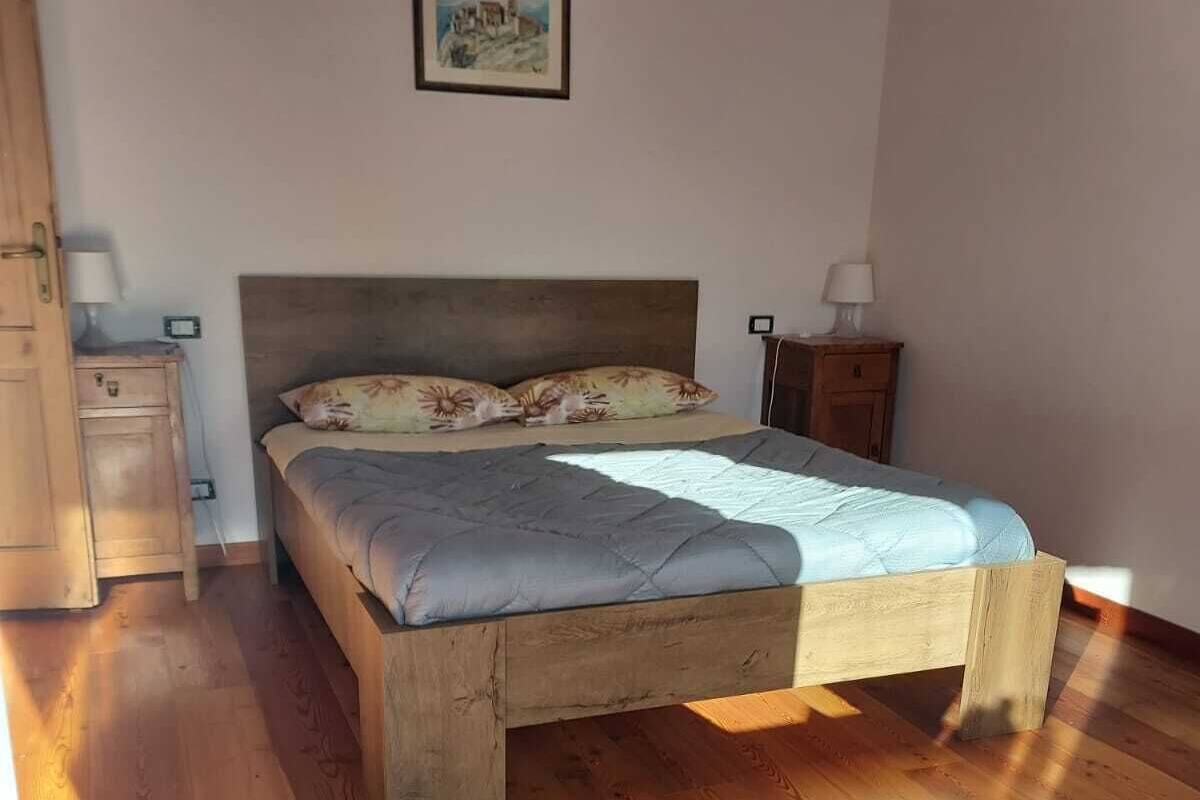 Un dormitorio con una cama de madera, dos mesitas de noche y una cómoda.