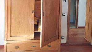 Een houten garderobe met een spiegeldeur, een klein plankje en een lade.