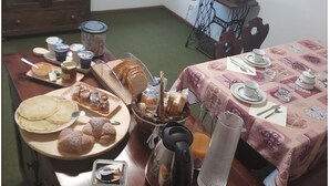 Een ontbijtruimte met een gedekte tafel, inclusief gebak, brood en toevoegingen.
