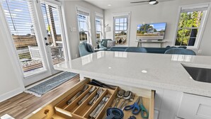 Eine moderne Küche mit eingebauter Schubladeneinteilung für Küchenutensilien, einem großen Fenster mit Jalousien und einem Fernseher an der Wand.