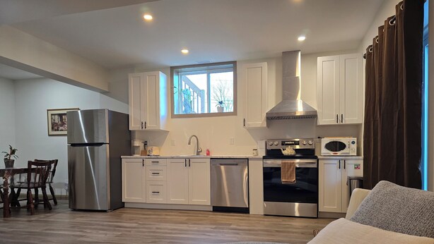 A compact kitchen with white cabinets, a stainless steel refrigerator, and a built-in oven.