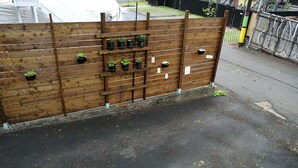 A wooden fence with multiple planters and a metal gate. - Montreal Mile-Ex close to MIL (Montréal)