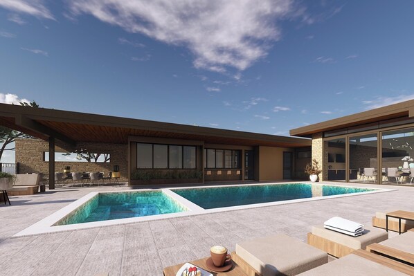 Un área de piscina moderna al aire libre, con un muro de piedra, asientos de descanso y un porche cubierto.