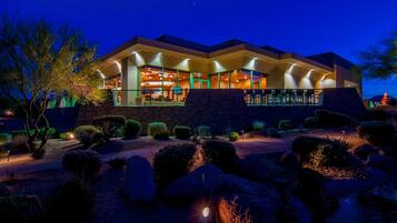 A modern building with a large open patio area, stone walls, and well-lit interior spaces.