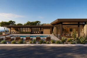 Un hotel moderno con piscina, mobiliario exterior y fachada de piedra.