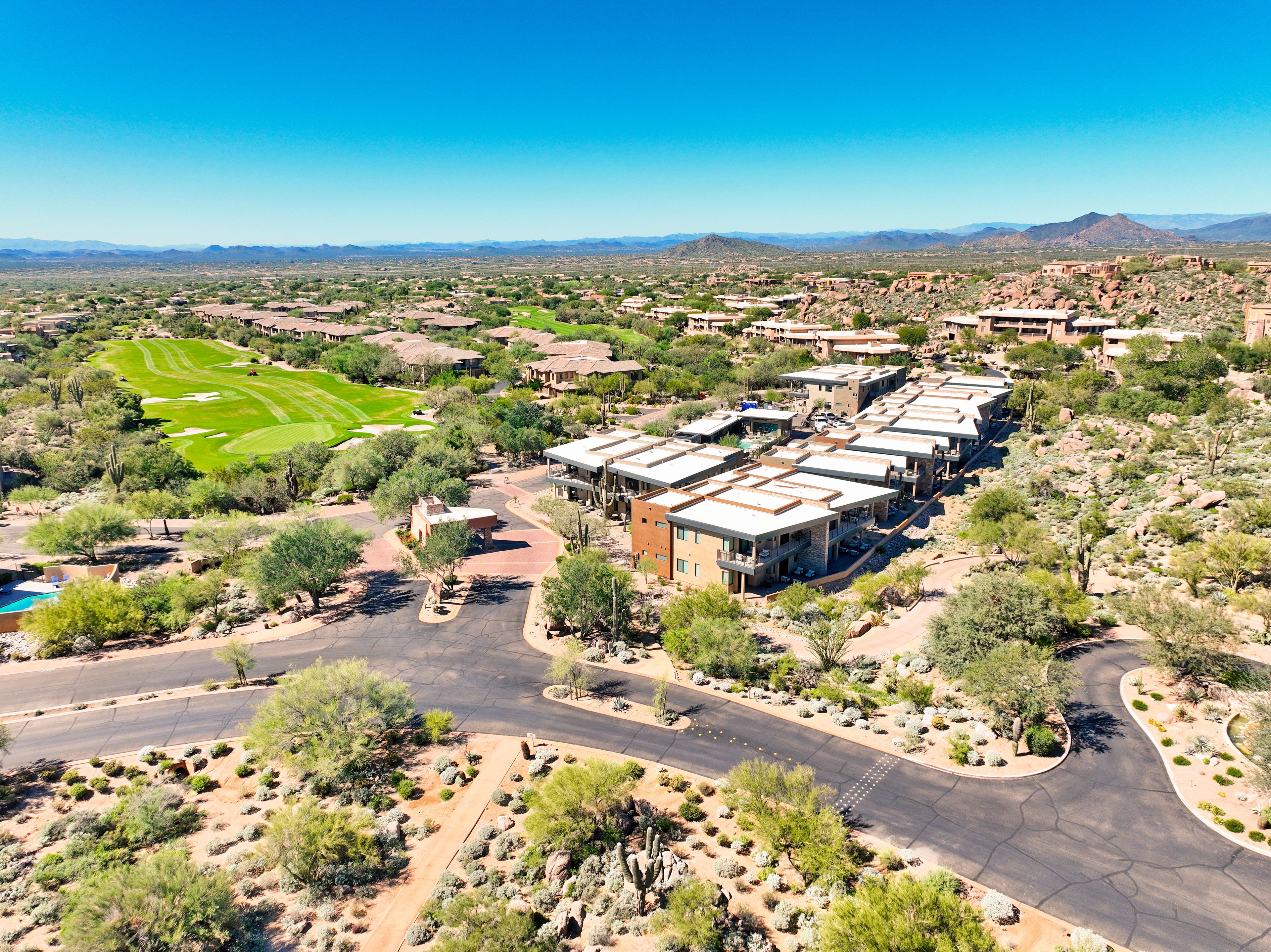 A residential area with multiple buildings, a golf course, and a desert landscape.