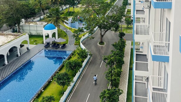 A modern hotel with a swimming pool, a covered area with umbrellas, and a view of a lush green landscape. - Celestial Villas and Apartments (Negombo)