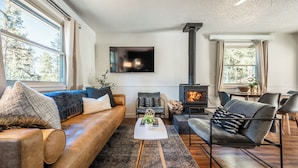 Een moderne woonkamer met een bank, fauteuils, een salontafel en een open haard.