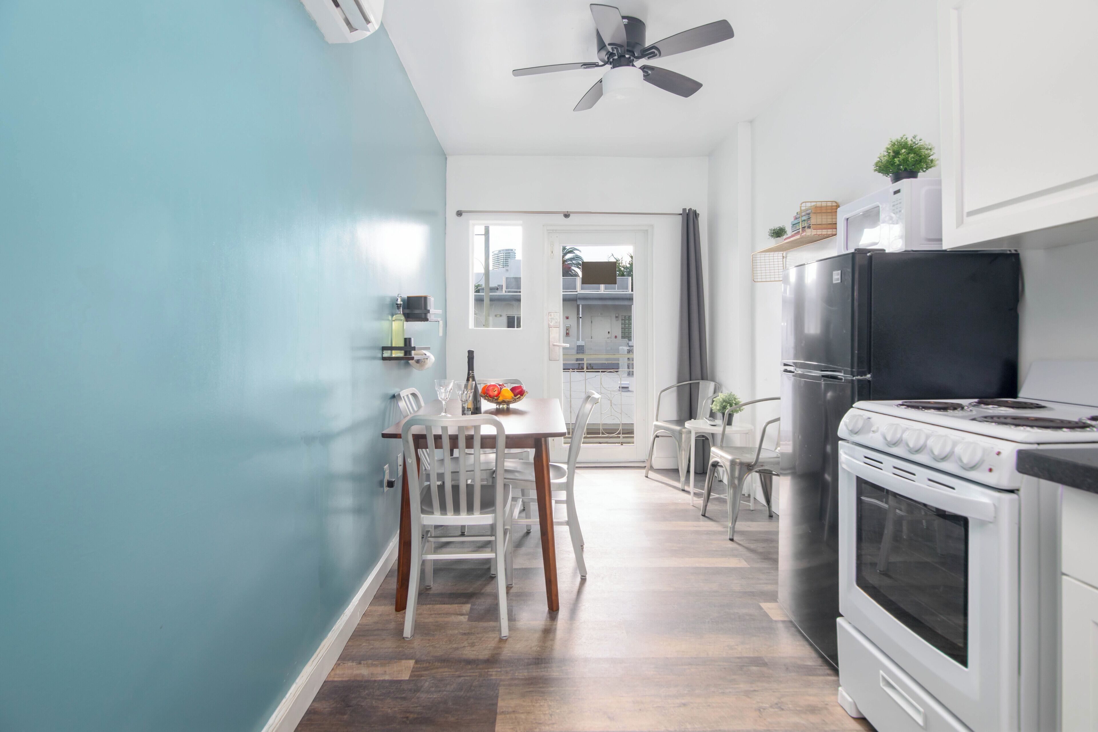 Una cucina compatta con zona pranzo, ventilatore a soffitto e vista attraverso la porta.