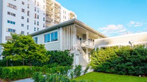 A modern building with a white facade, multiple balconies, and a well-maintained garden area. - Boutique Apartments Flamingo (Miami Beach)