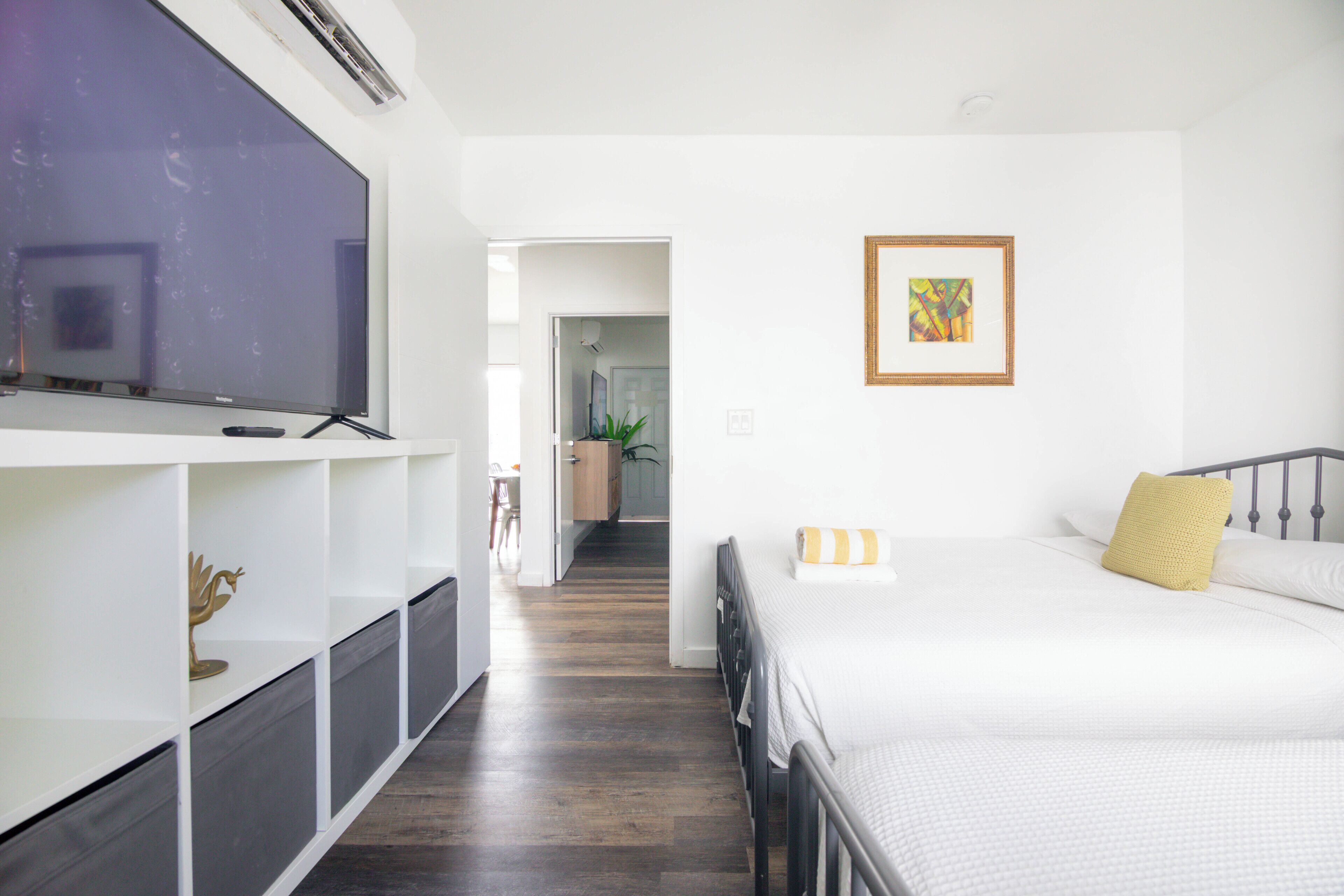 A bedroom with a bed, a TV, and a framed picture on the wall.