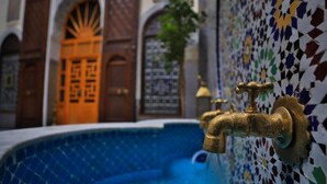 A pool with a decorative wall and a golden faucet. - Riad SOULTANA every stay tells a story (Fes)