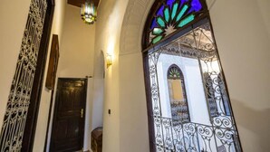An interior with a dark wooden door, a decorative wrought iron gate, and a stained glass window with a geometric pattern. - Riad SOULTANA every stay tells a story (Fes)