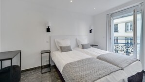 A modern bedroom with a large bed, two bedside tables, and a view of a balcony.