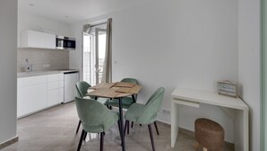 A modern kitchen with white cabinets, a built-in oven, and a dining area with a table and chairs.