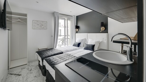A modern hotel room with a large bed, a built-in sink, and a TV mounted on the wall. - Double-bed or twins Studio in Apart'hotel Le Bellevue (Paris)