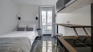 A modern hotel room with a bed, a desk, a TV, and a window with curtains. - Double-bed or twins Studio in Apart'hotel Le Bellevue (Paris)