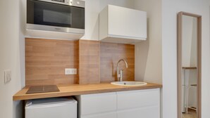 Una kitchenette compacta con horno integrado, un lavamanos y un refrigerador pequeño.