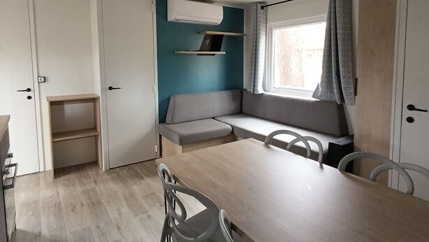 Une cuisine compacte avec un coin repas, des étagères intégrées et une fenêtre avec des rideaux.