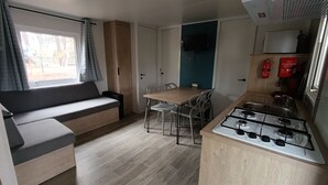 Une petite cuisine équipée d’une cuisinière à gaz, d’une table à manger avec des chaises et d’un canapé.