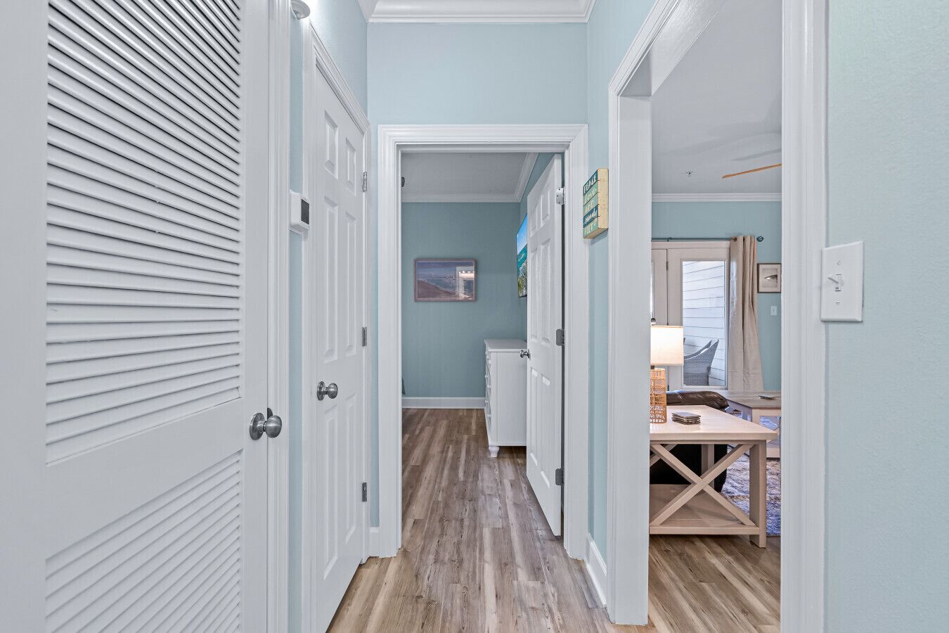 A hallway with white doors, a wooden floor, and a small table with a lamp.