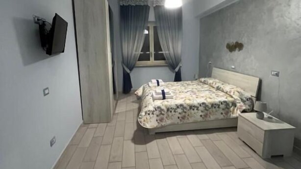 A bedroom with a bed, bedside table, and a TV mounted on the wall. - Vicolo 55 (Naples)