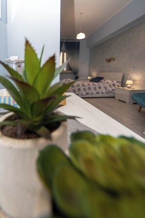 A modern bedroom with a bed, bedside tables, a nightstand, a potted plant, and a hanging light fixture. - Vicolo 55 (Naples)