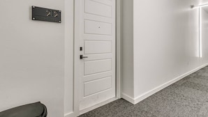 Un couloir avec une porte blanche et une plaque indiquant le numéro de la pièce : 212.