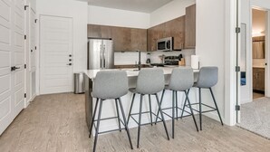 Une cuisine moderne dotée d’un îlot central, de tabourets de bar et d’appareils électroménagers en acier inoxydable.