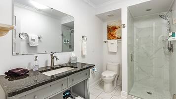 A modern bathroom with a large mirror, a sink, a toilet, and a glass-enclosed shower.