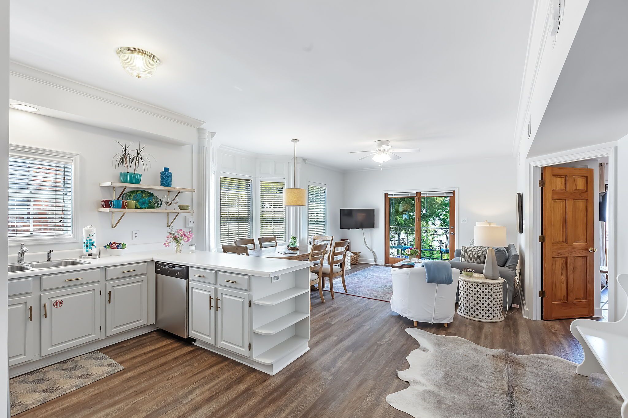 A spacious kitchen with white cabinetry, a central island, and a dining area with chairs.
